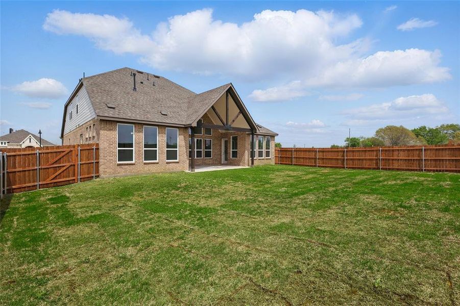 Back of house featuring a fenced backyard, brick siding, a yard, and a patio area Back of house featuring a fenced backyard, brick siding, a yard, and a patio area