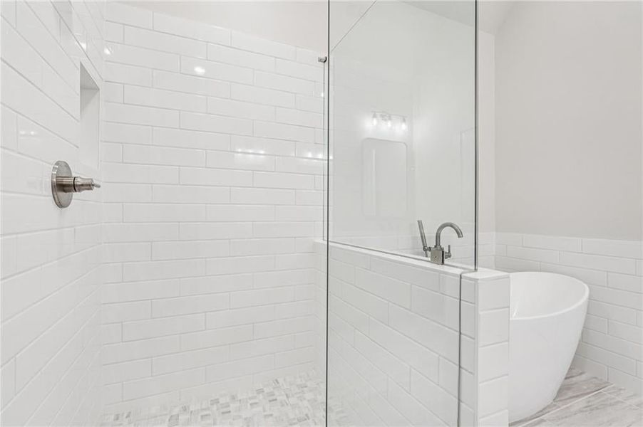 Stunning and bright tile in primary bathroom - subway tile set on 1/3 horizontal pattern with decorative small tile floor tiles tie in the colors from the flooring in bathroom