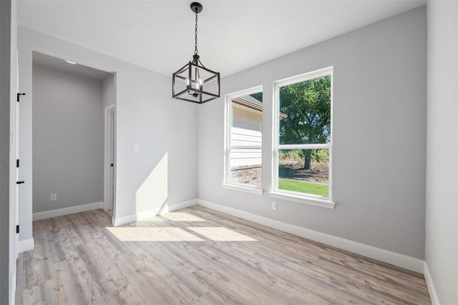 Unfurnished dining area featuring a chandelier, plenty of natural light, and light wood-style floors Unfurnished dining area featuring a chandelier, plenty of natural light, and light wood-style floors