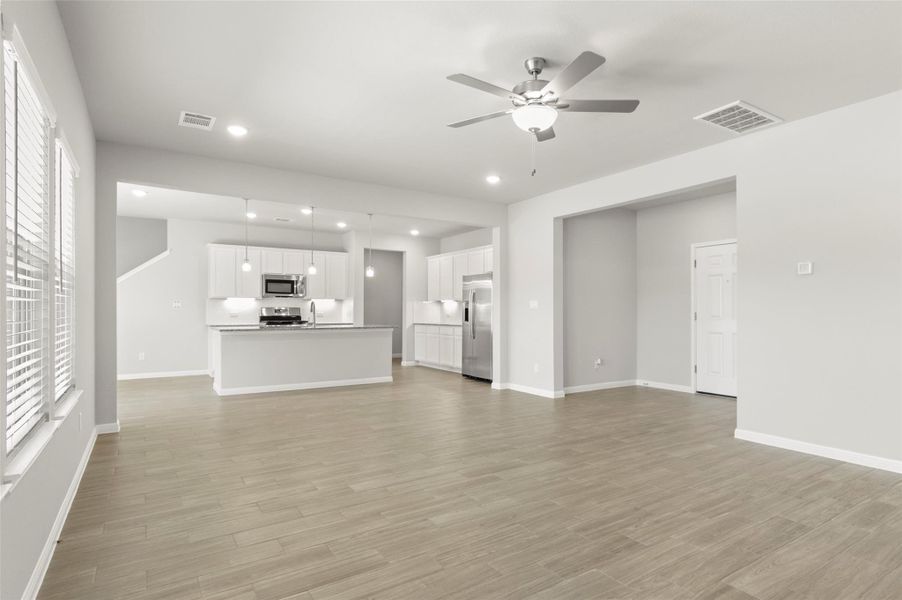 Unfurnished living room with ceiling fan, healthy amount of natural light, baseboards, light wood-type flooring, and recessed lighting