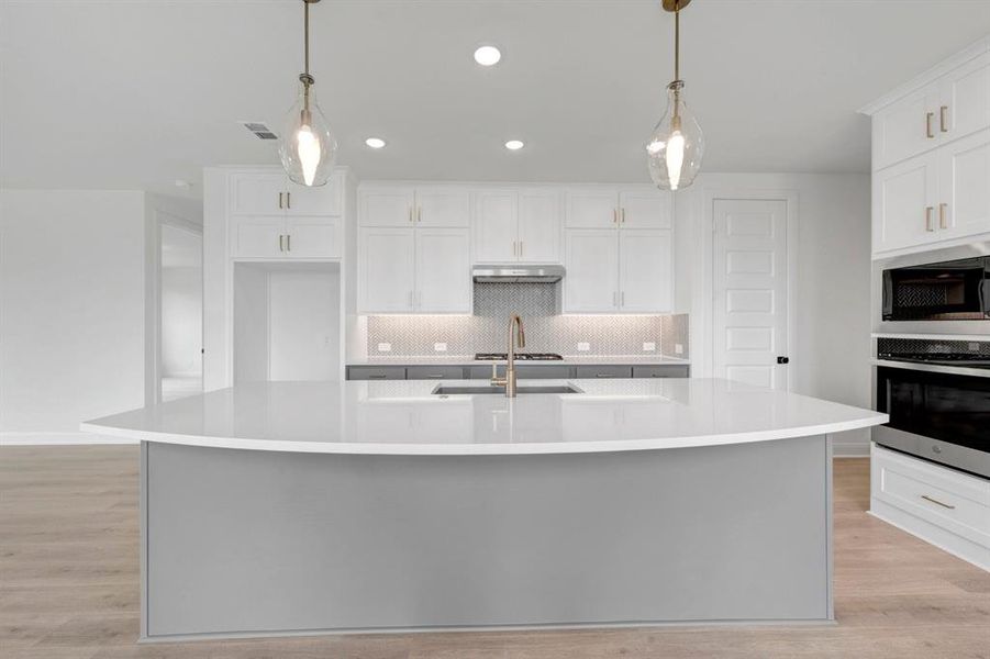 Kitchen featuring a curved central island with a light grey base and white countertop