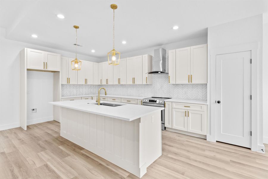 Kitchen with hanging light fixtures, electric range, tasteful backsplash, a center island with sink, and recessed lighting