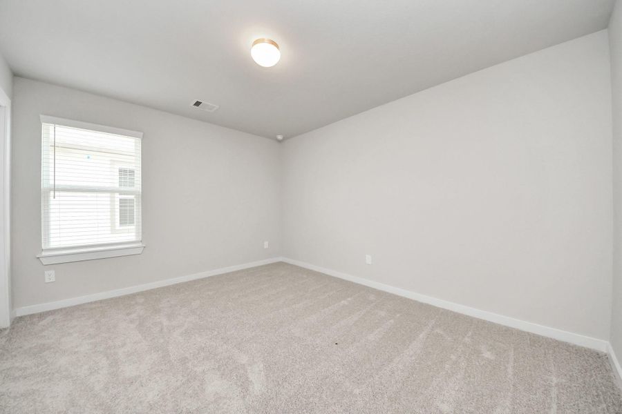 Secondary bedroom features plush carpeting, large windows that let in plenty of natural light, bright paint, and spacious closets. Sample photo of completed home with similar floor plan. Actual colors and selections may vary.