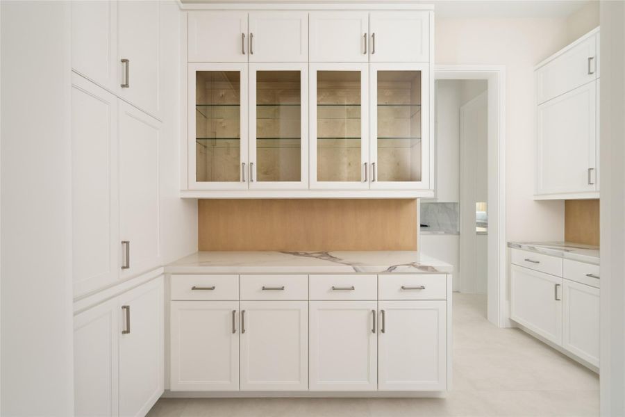 Elegant butler’s pantry featuring glass display cabinetry, quartzite surfaces, and built-in storage throughout.