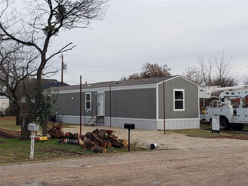 Front street and yard of manufactured home. Carport under construction