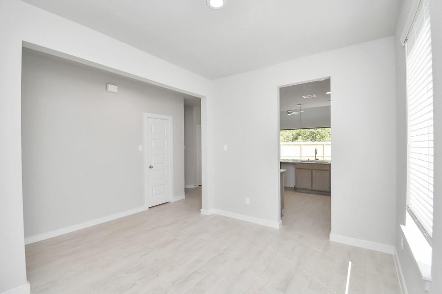 Create lasting memories with your family and friends at the dining table! This expansive dining room showcases sophisticated flooring, custom paint, and seamlessly connects to the family room and kitchen, providing an open and inviting atmosphere. Sample photo of completed home with similar floor plan. Actual colors and selections may vary.
