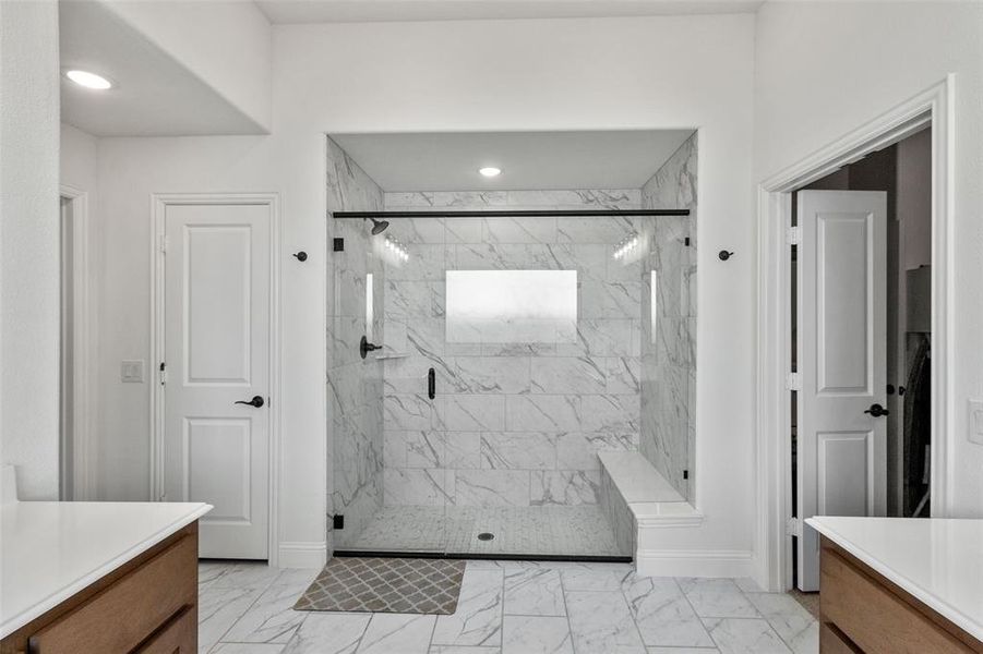 Full bathroom with vanity, a marble finish shower, and light marble finish floors