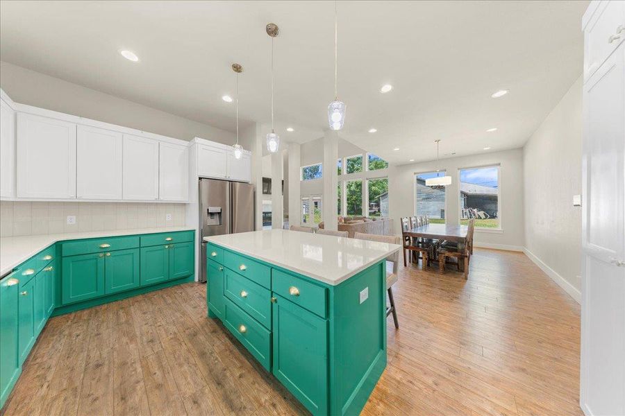 Kitchen featuring white cabinets, green cabinetry, backsplash, a center island, and light wood finished floors Kitchen featuring white cabinets, green cabinetry, backsplash, a center island, and light wood finished floors