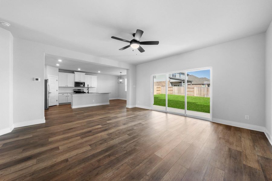 An open-concept living space with sleek flooring flows effortlessly into the well-equipped kitchen and a fenced backyard. An open-concept living space with sleek flooring flows effortlessly into the well-equipped kitchen and a fenced backyard.