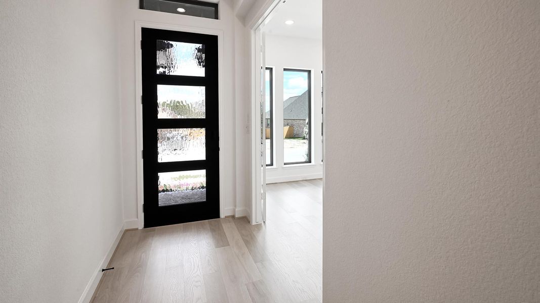 Entrance foyer with a textured wall and light wood-style flooring Entrance foyer with a textured wall and light wood-style flooring