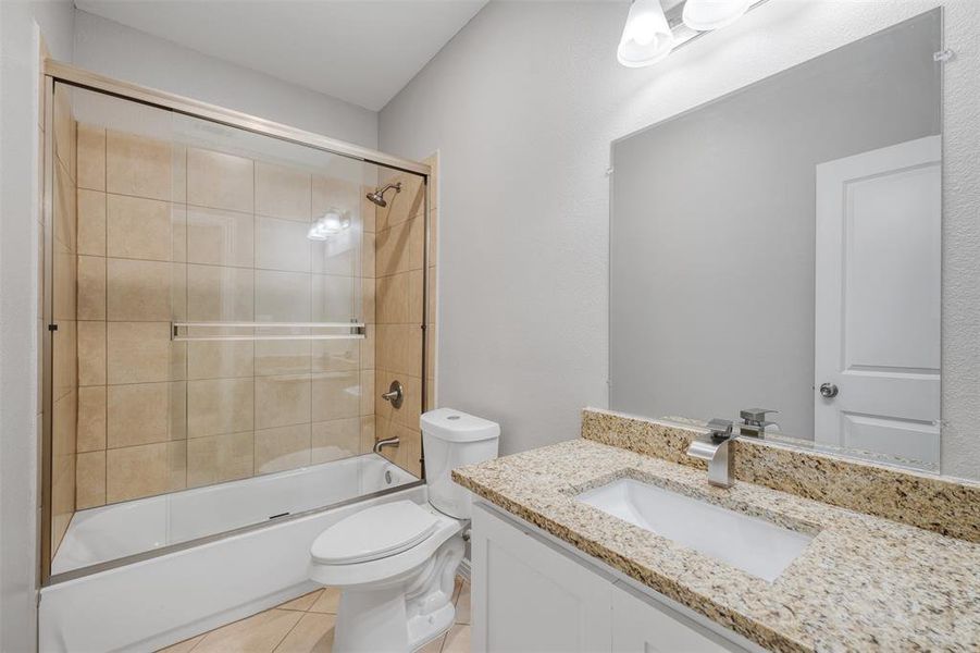 Full bathroom featuring tile patterned flooring, vanity, enclosed tub / shower combo, and toilet