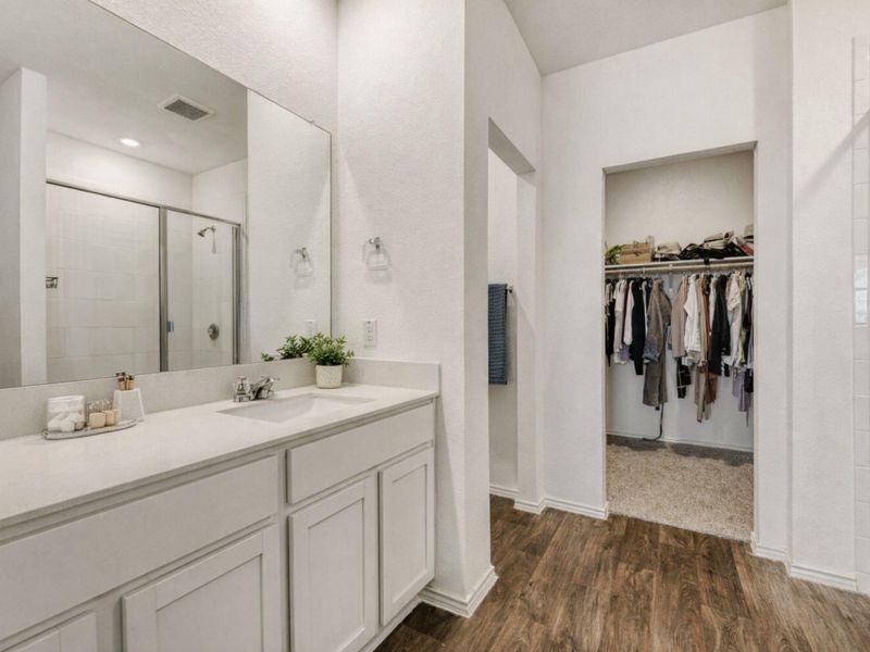 Bathroom featuring a spacious closet, vanity, a shower stall, and dark wood-style flooring