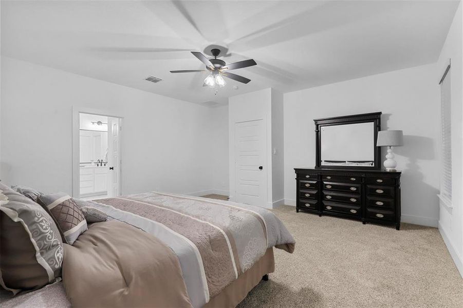 Carpeted bedroom featuring ceiling fan and connected bathroom