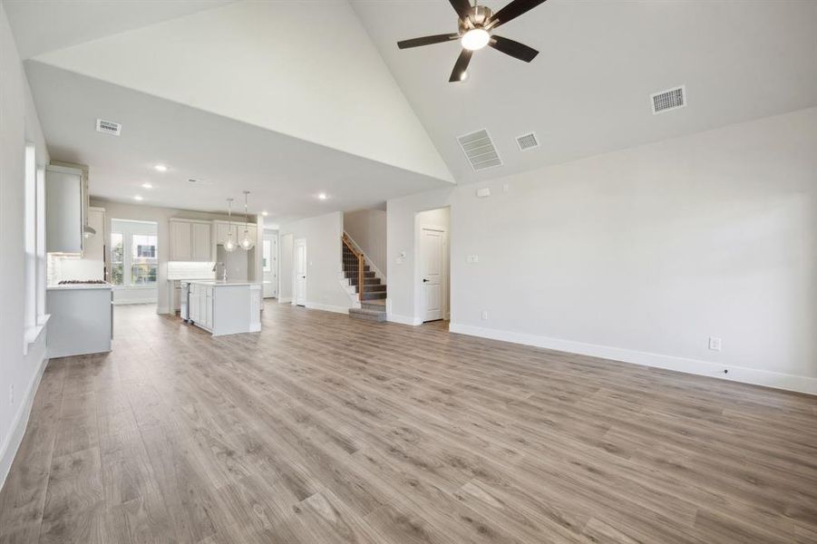 Unfurnished living room with ceiling fan, light hardwood / wood-style flooring, and high vaulted ceiling