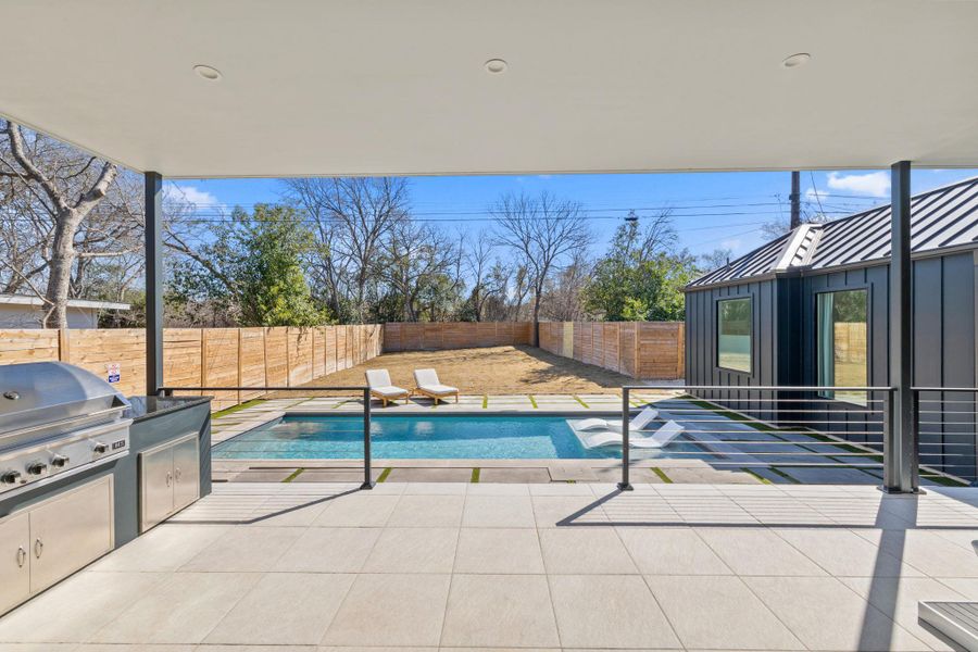 View of swimming pool with patio surround, exterior kitchen, and a fenced backyard