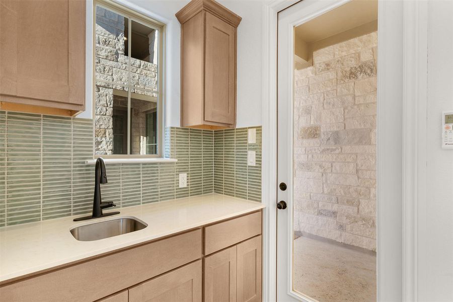 Kitchen featuring light wood finish cabinetry, light stone countertops, and tasteful backsplash