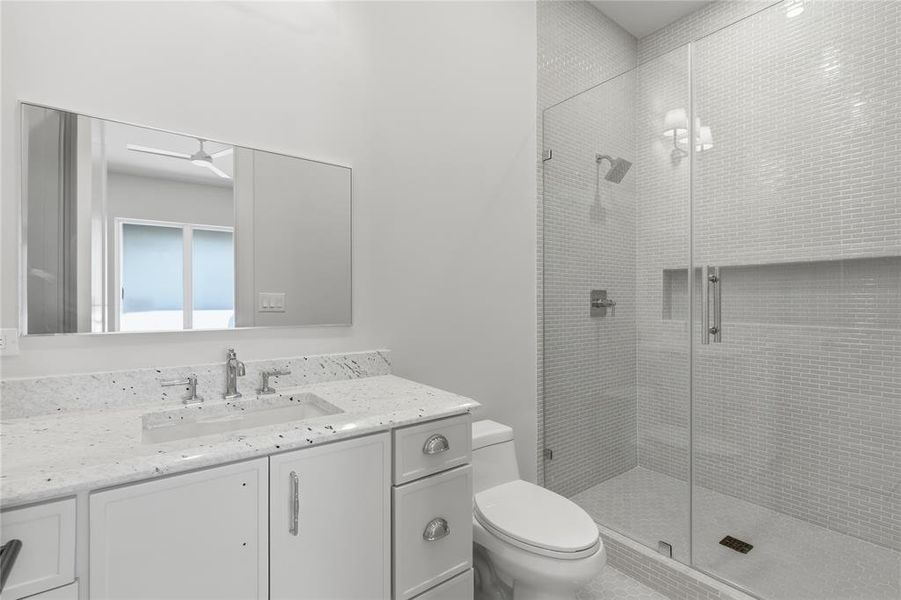 Secondary bath with glass-enclosed shower, mosaic tile surround, and quartz vanity Secondary bath with glass-enclosed shower, mosaic tile surround, and quartz vanity