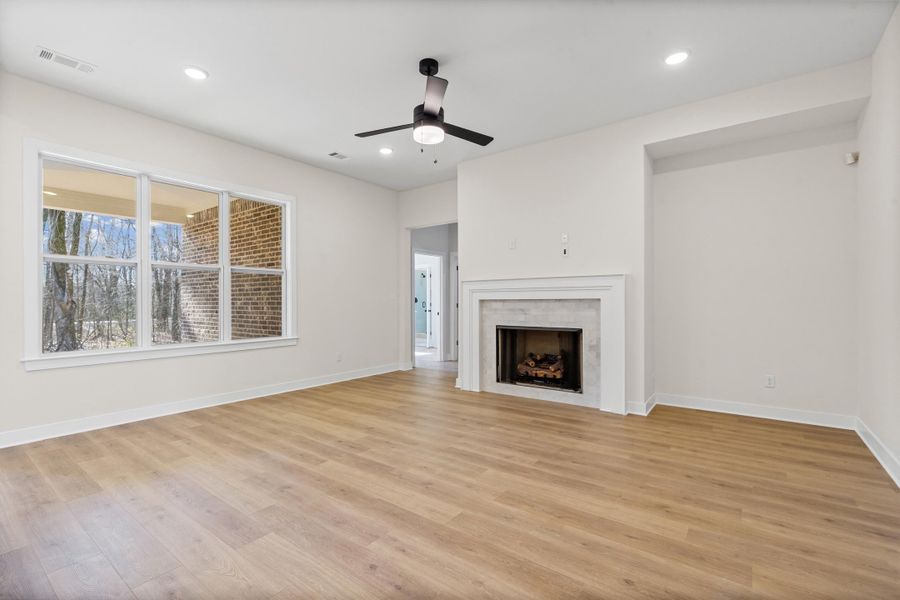Unfurnished living room with a ceiling fan, light wood finished floors, recessed lighting, and a fireplace Unfurnished living room with a ceiling fan, light wood finished floors, recessed lighting, and a fireplace