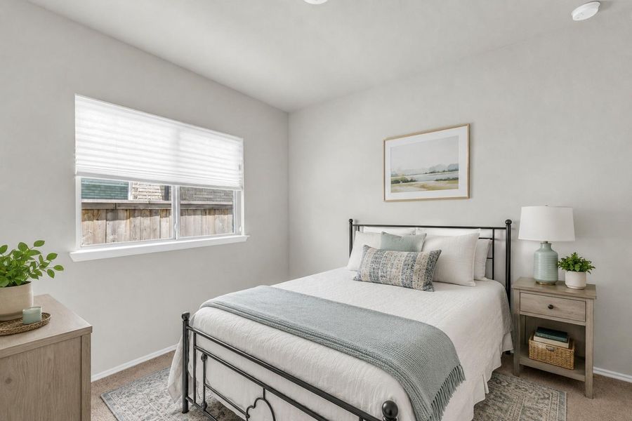 A bright secondary bedroom offers soft plush carpeting and a large window looking out toward the side yard.**Virtually staged A bright secondary bedroom offers soft plush carpeting and a large window looking out toward the side yard.**Virtually staged