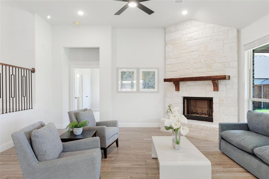 Living room with floor-to-ceiling stone fireplace, wood mantel, gray seating, and ceiling fan on light wood-look floors Living room with floor-to-ceiling stone fireplace, wood mantel, gray seating, and ceiling fan on light wood-look floors