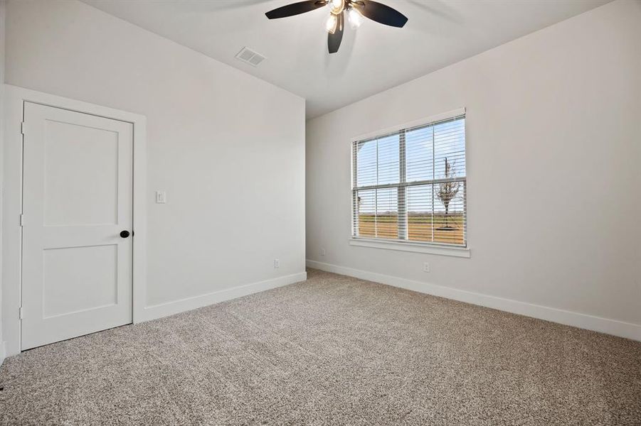 Carpeted spare room featuring baseboards, visible vents, and ceiling fan