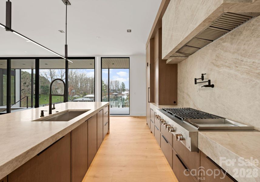 Kitchen featuring a waterfall island, custom cabinetry, and high-end appliances. Kitchen featuring a waterfall island, custom cabinetry, and high-end appliances.