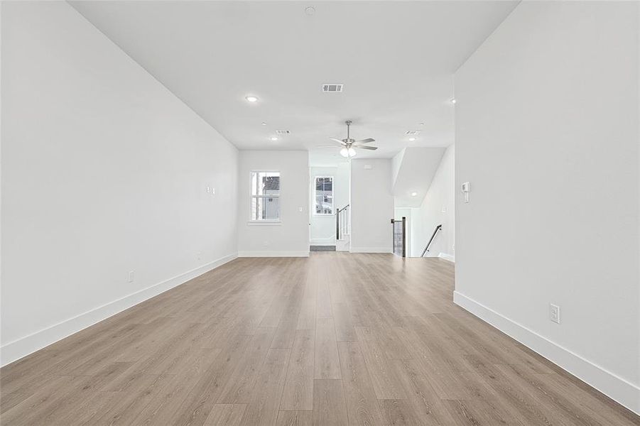 Bright and open living space featuring light-toned flooring, white walls, recessed lighting, and a ceiling fan