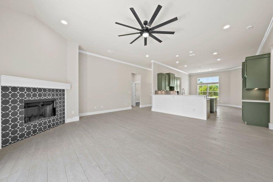 Unfurnished living room with ornamental molding, a ceiling fan, a tile fireplace, recessed lighting, and light wood finished floors Unfurnished living room with ornamental molding, a ceiling fan, a tile fireplace, recessed lighting, and light wood finished floors