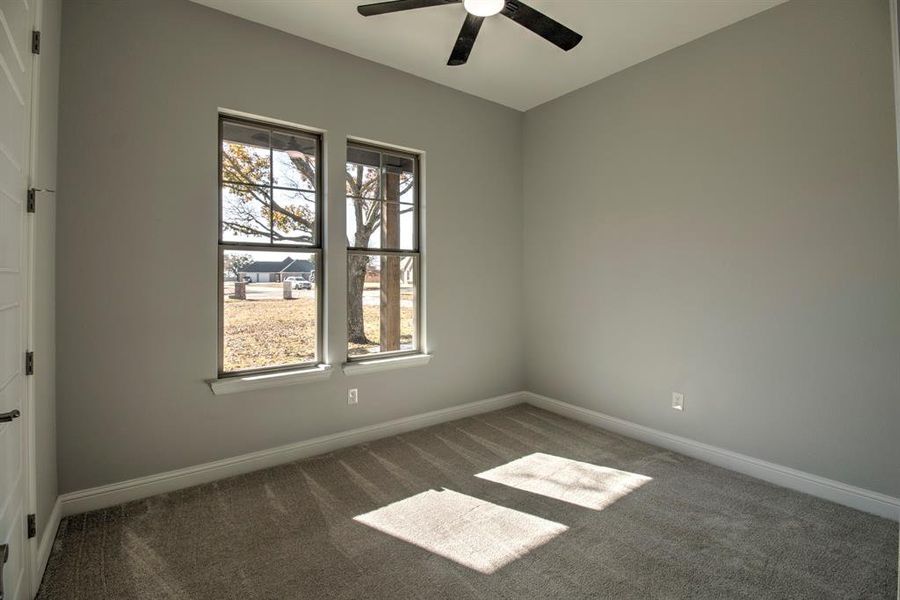 Empty room with dark colored carpet and ceiling fan