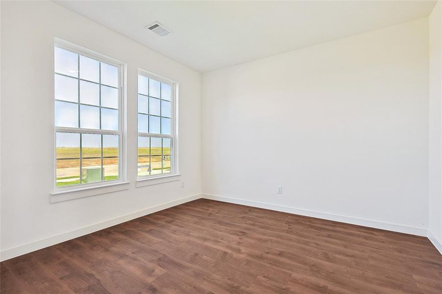 Spare room featuring dark wood-type flooring and baseboards