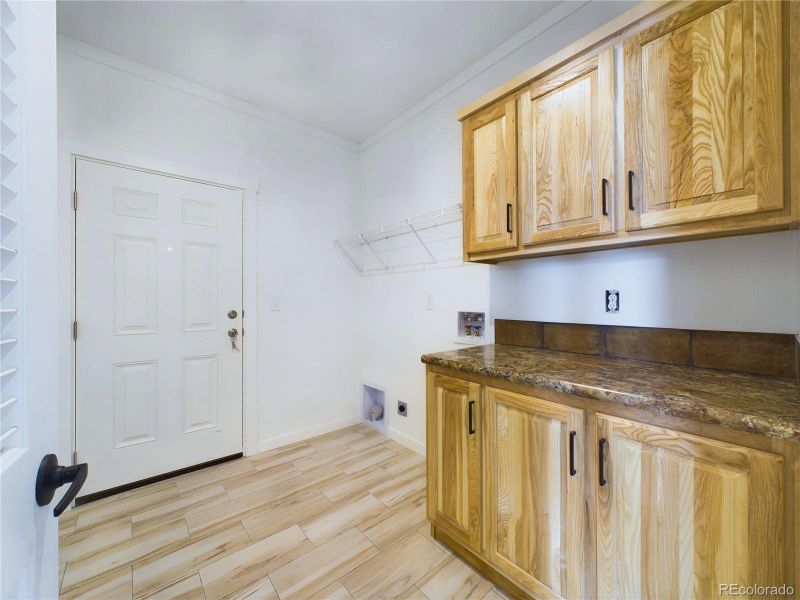 Washroom with electric dryer hookup, washer hookup, cabinets