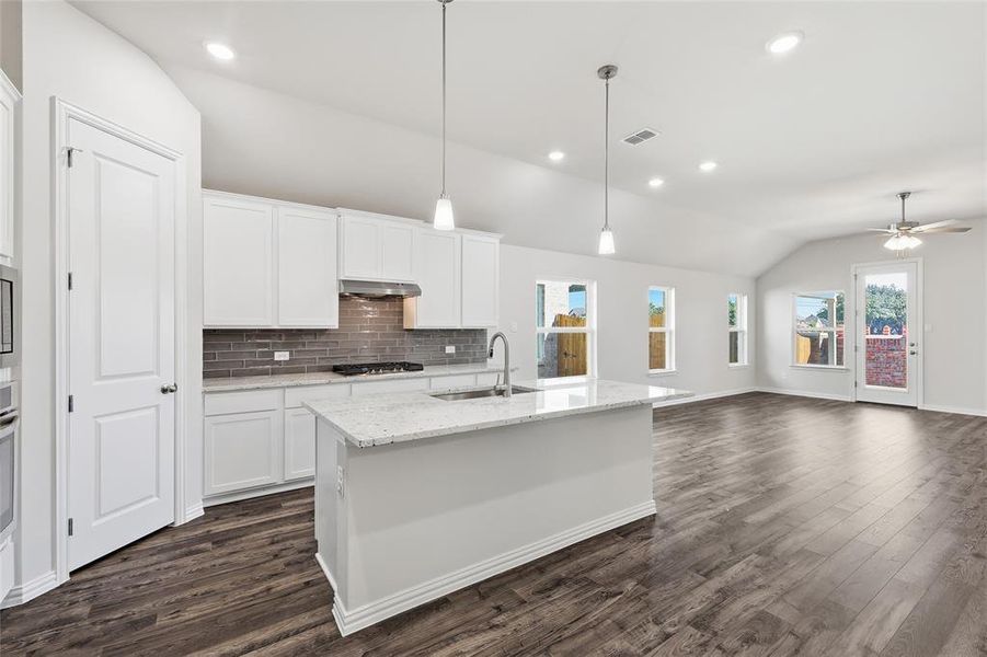 Open-concept living space featuring wood-finish flooring and a vaulted ceiling