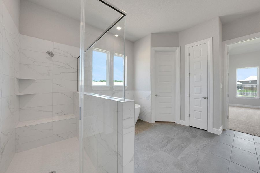 Bathroom featuring a marble finish shower, a freestanding bath, and recessed lighting