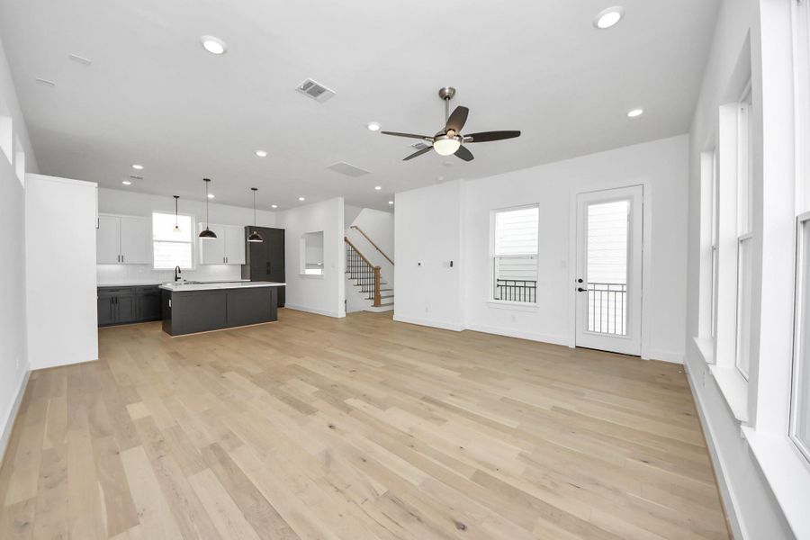 Step into the bright second-level living room, featuring hard wood floors, a ceiling fan, and recessed lighting. French doors lead to a private balcony, enhancing the room's airy ambiance.