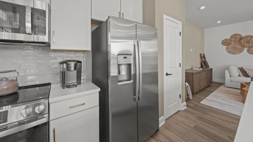 The Rochester Plan by DRB homes kitchen with white cabinets, silver appliances and gold features in Charlotte, NC.