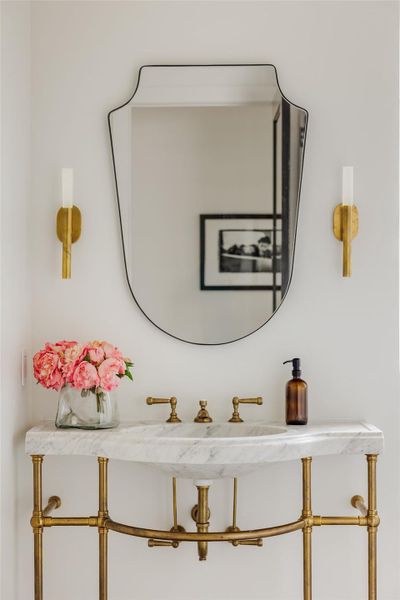 A jewel box of design, this powder bath pairs sculptural brass detailing with marble surfaces and artful accents. A perfect reflection of the home’s refined personality, where every material choice feels intentional and elevated. A jewel box of design, this powder bath pairs sculptural brass detailing with marble surfaces and artful accents. A perfect reflection of the home’s refined personality, where every material choice feels intentional and elevated.