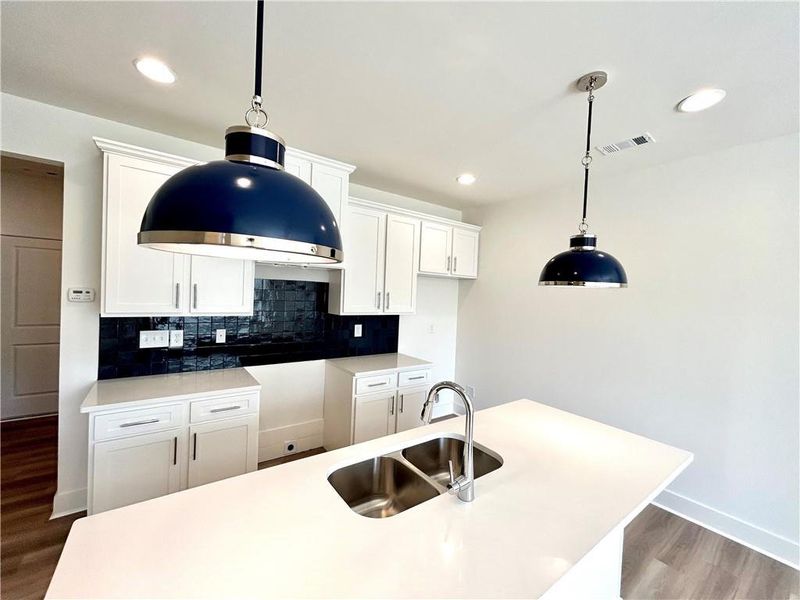 Kitchen featuring sink, pendant lighting, light hardwood / wood-style flooring, and white cabinetry