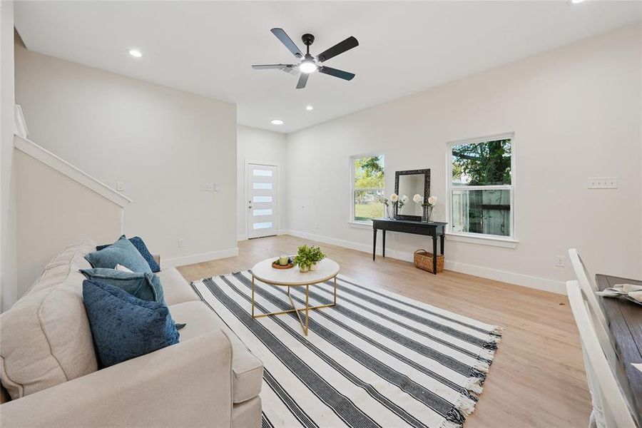 Living area with recessed lighting, light wood finished floors, ceiling fan, and stairway Living area with recessed lighting, light wood finished floors, ceiling fan, and stairway
