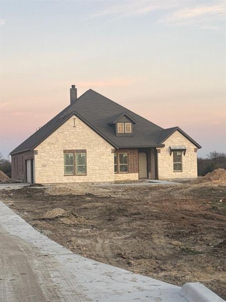 View of front of property featuring stone siding, a chimney, and a garage