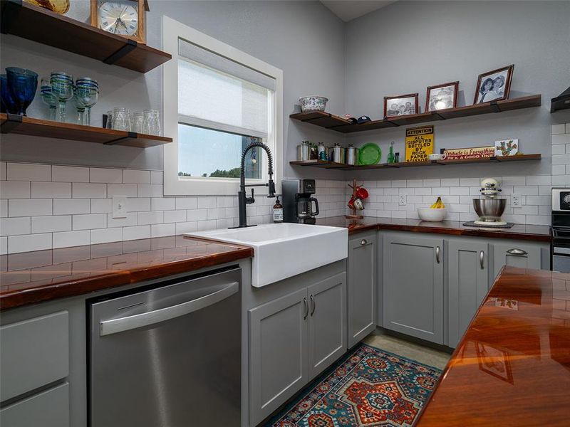 Kitchen featuring butcher block countertops, stainless steel appliances, gray cabinets, backsplash, and open shelves Kitchen featuring butcher block countertops, stainless steel appliances, gray cabinets, backsplash, and open shelves