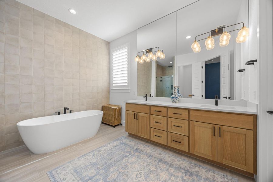 Bathroom featuring a stall shower, double vanity, tile walls, a freestanding tub, and recessed lighting