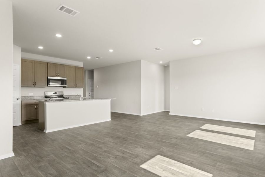 Image of a dining room with dark vinyl flooring, cream walls, and a kitchen with a center island