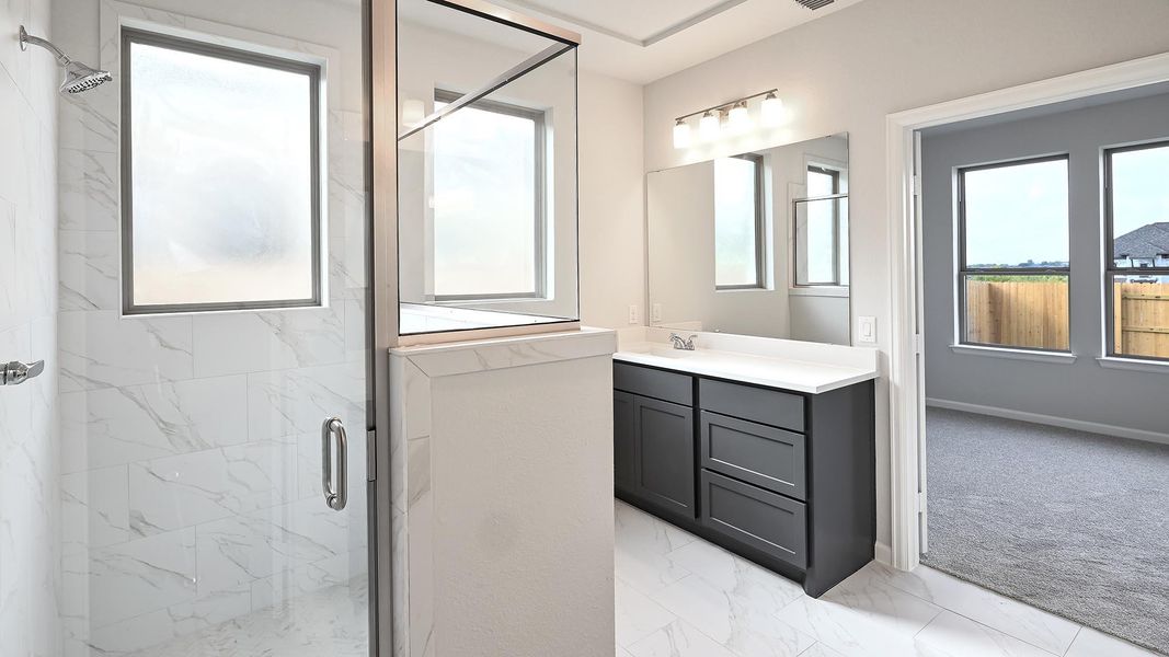 Full bath featuring healthy amount of natural light, a marble finish shower, light marble finish floors, and vanity Full bath featuring healthy amount of natural light, a marble finish shower, light marble finish floors, and vanity