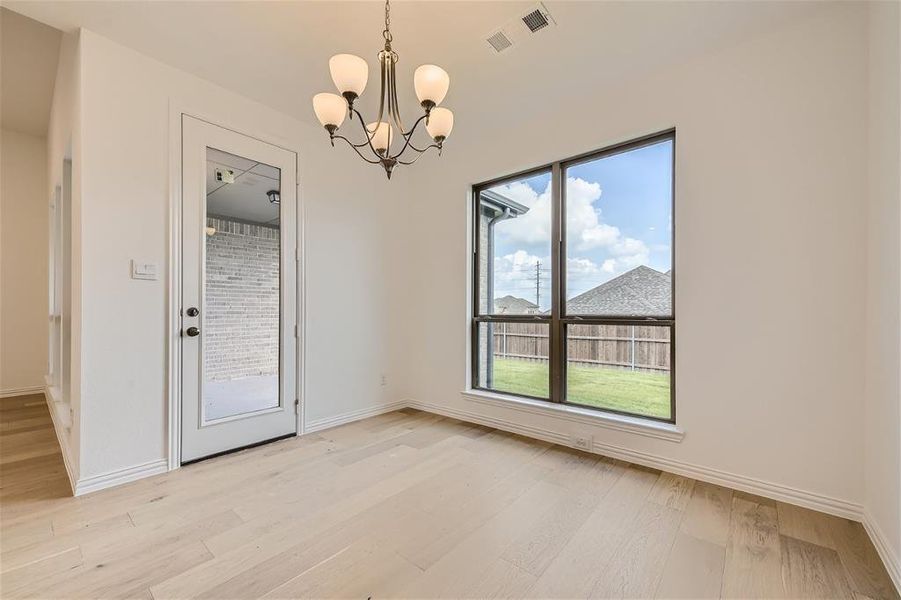 Unfurnished room with an inviting chandelier and light hardwood / wood-style flooring