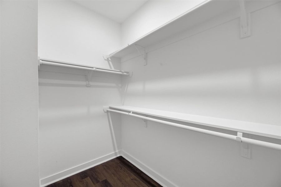 Multiple shelves and hanging rods, ideal for organized storage. The dark wood flooring adds a touch of elegance.