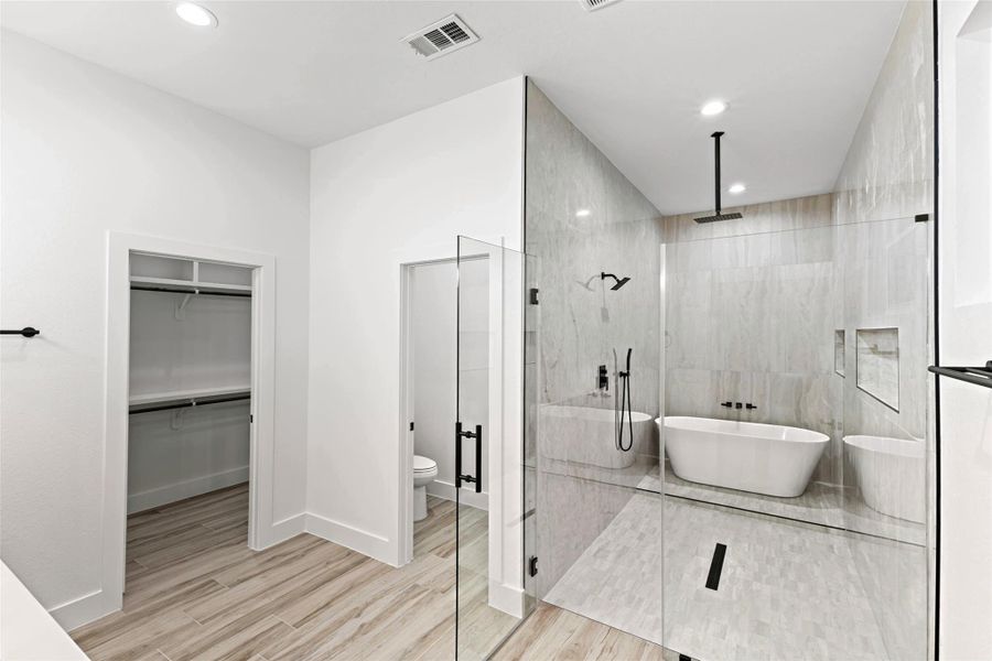 This bathroom features a spacious glass-enclosed shower and a modern freestanding bathtub. It includes a sleek, minimalist design with light wood flooring and a walk-in closet. This bathroom features a spacious glass-enclosed shower and a modern freestanding bathtub. It includes a sleek, minimalist design with light wood flooring and a walk-in closet.