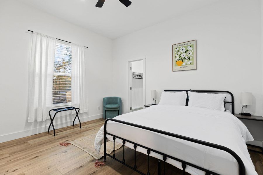 Bedroom with light wood finished floors, ceiling fan, and a spacious closet