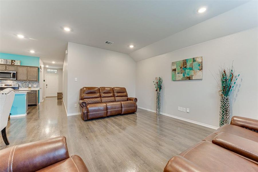 Living room with vaulted ceiling and light hardwood / wood-style flooring