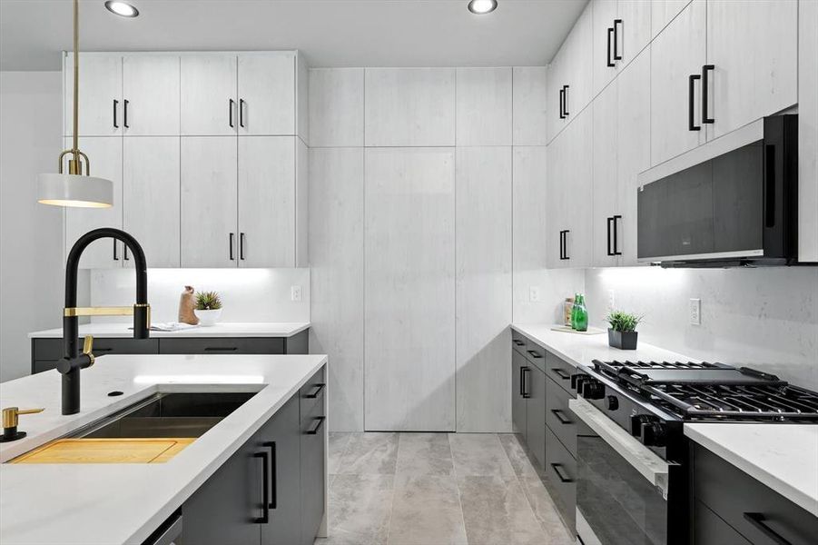 Kitchen featuring gas stove, decorative light fixtures, recessed lighting, light stone countertops, and modern cabinets