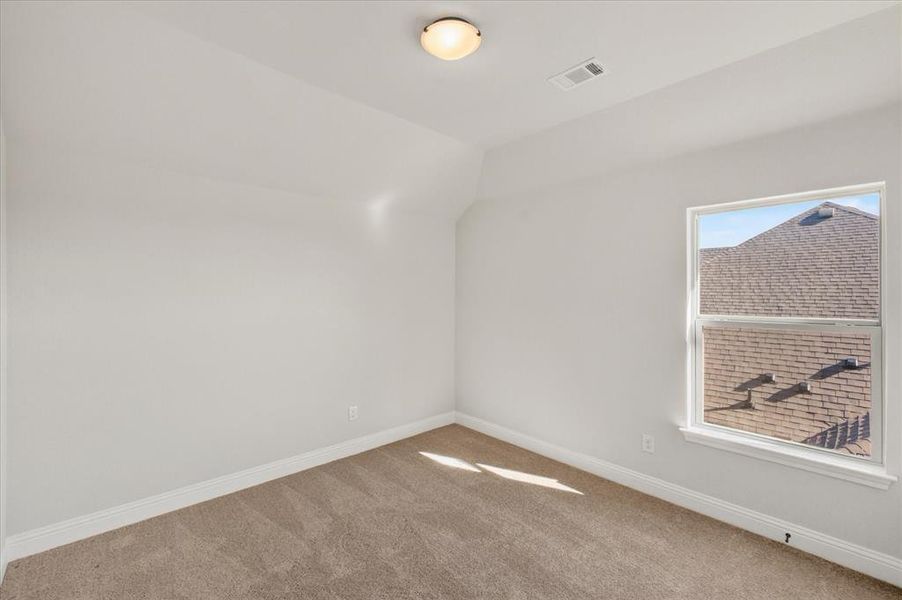 Carpeted empty room featuring baseboards and vaulted ceiling Carpeted empty room featuring baseboards and vaulted ceiling